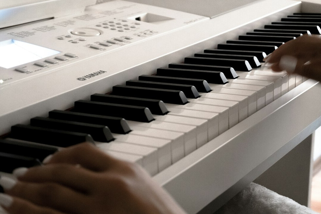 Close-up of hands typing on a laptop keyboard with code on the screen
