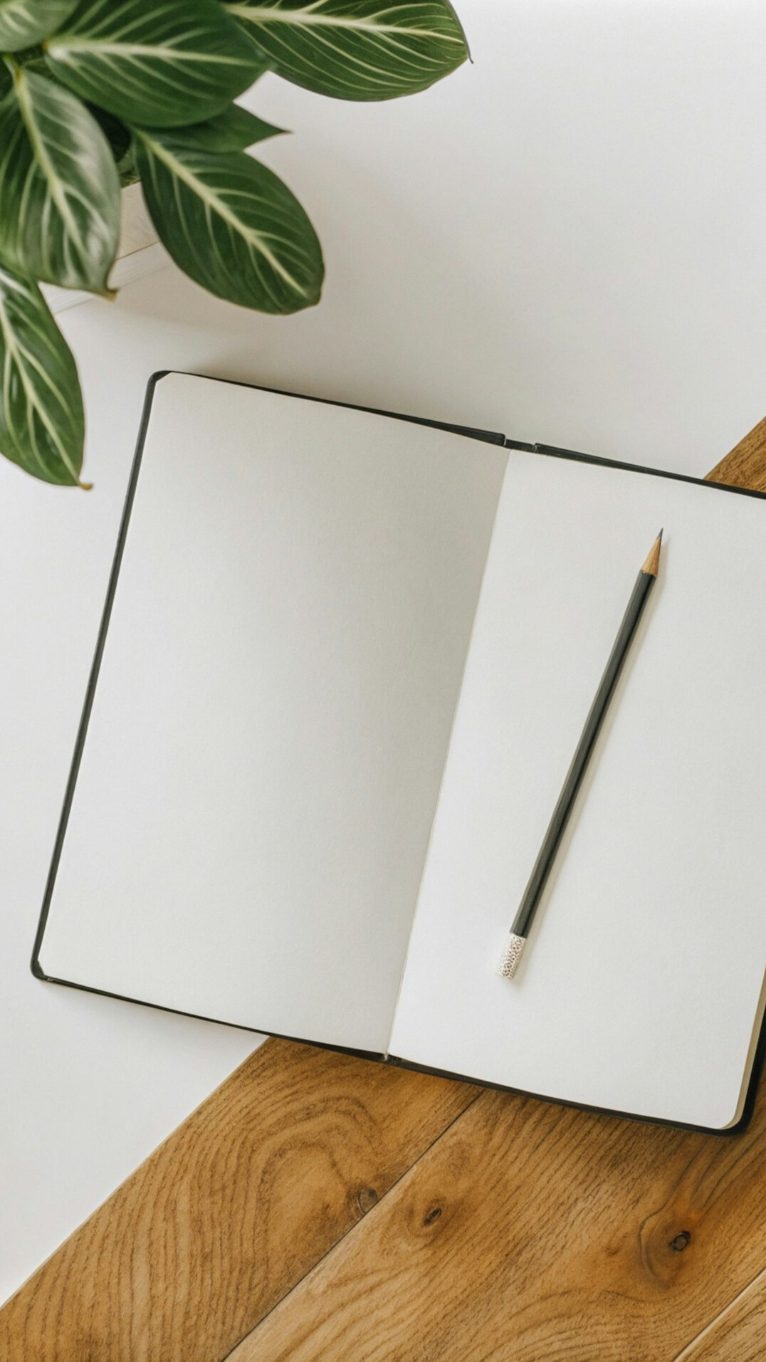 Overhead view of a desk with an open laptop, notebook, and pen arranged neatly